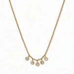 A Twinkle Five Drop White Cubic Zirconia Necklace by Skōsh Jewelry, featuring five small bezel-set clear stones dangling from the center of a fine gold chain, displayed against a white background.