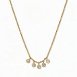 A Twinkle Five Drop White Cubic Zirconia Necklace by Skōsh Jewelry, featuring five small bezel-set clear stones dangling from the center of a fine gold chain, displayed against a white background.