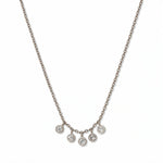A Twinkle Five Drop White Cubic Zirconia Necklace by Skōsh Jewelry, featuring five small bezel-set clear stones dangling from the center of a fine sterling silver chain, displayed against a white background.