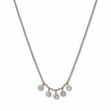 A Twinkle Five Drop White Cubic Zirconia Necklace by Skōsh Jewelry, featuring five small bezel-set clear stones dangling from the center of a fine sterling silver chain, displayed against a white background.