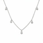 A Halo Bezel Set White Cubic Zirconia Drop Station Necklace by Skōsh Jewelry, featuring small bezel-set clear stones dangling at intervals along a fine sterling silver chain, displayed against a white background.