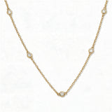 A Sanctuary Bezel Set White Cubic Zirconia Station Necklace by Skōsh Jewelry, featuring five small bezel-set clear stones spaced along a fine gold chain, displayed against a white background.