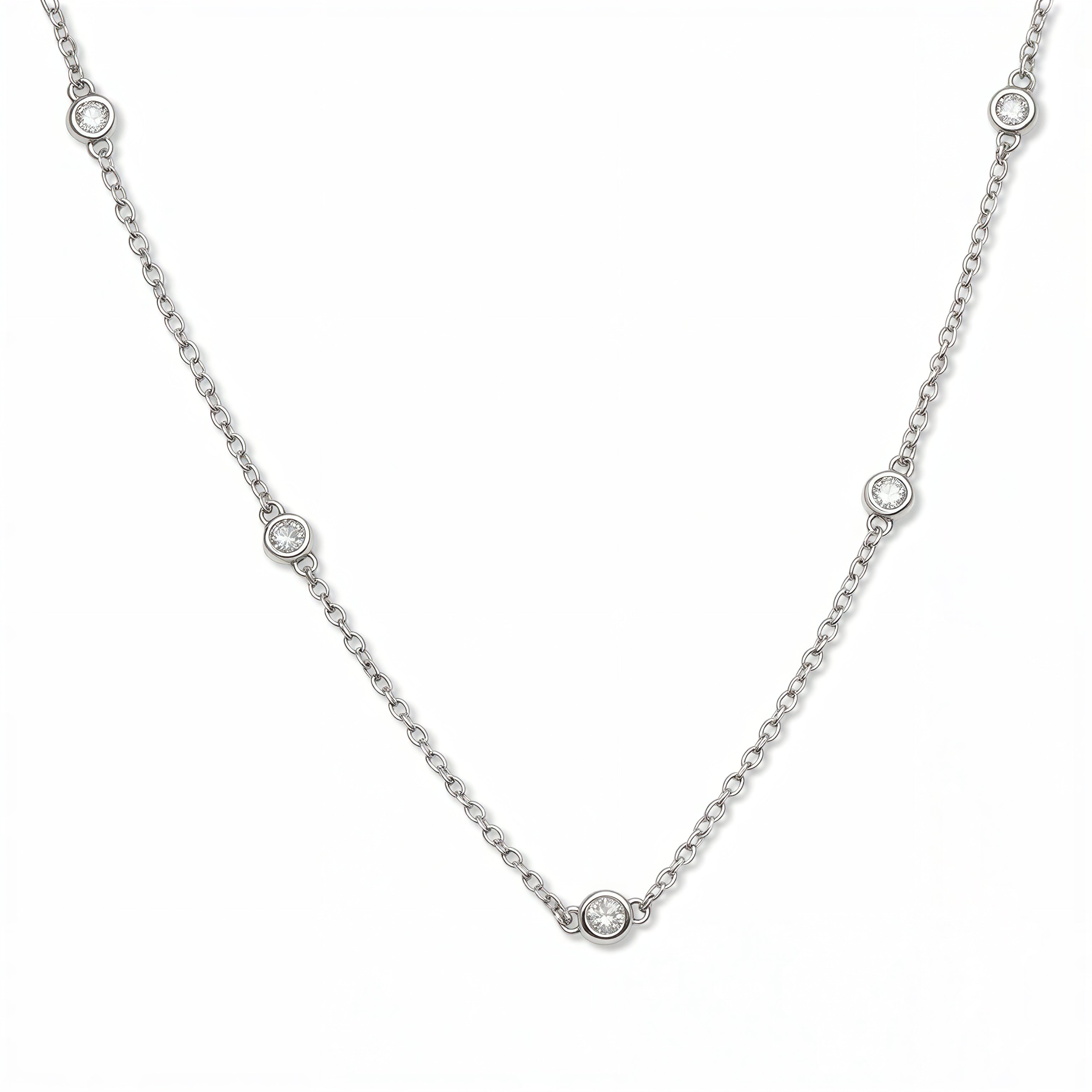 A Sanctuary Bezel Set White Cubic Zirconia Station Necklace by Skōsh Jewelry, featuring five small bezel-set clear stones spaced along a fine sterling silver chain, displayed against a white background.