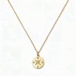 A True North Engraved Compass Pendant Necklace by Skōsh Jewelry, featuring a round compass medallion engraved with a compass rose on a fine gold chain, displayed against a white background.