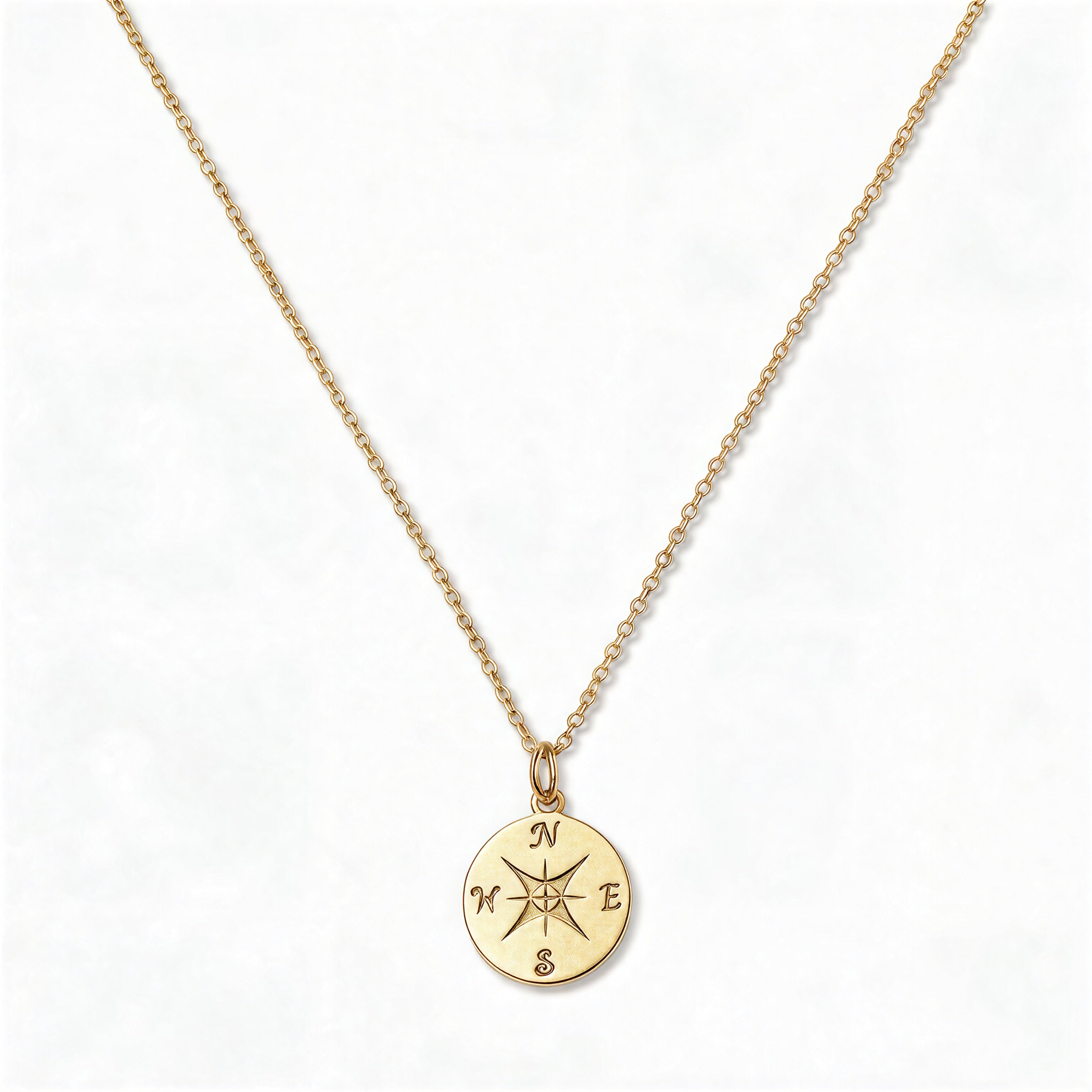 A True North Engraved Compass Pendant Necklace by Skōsh Jewelry, featuring a round compass medallion engraved with a compass rose on a fine gold chain, displayed against a white background.