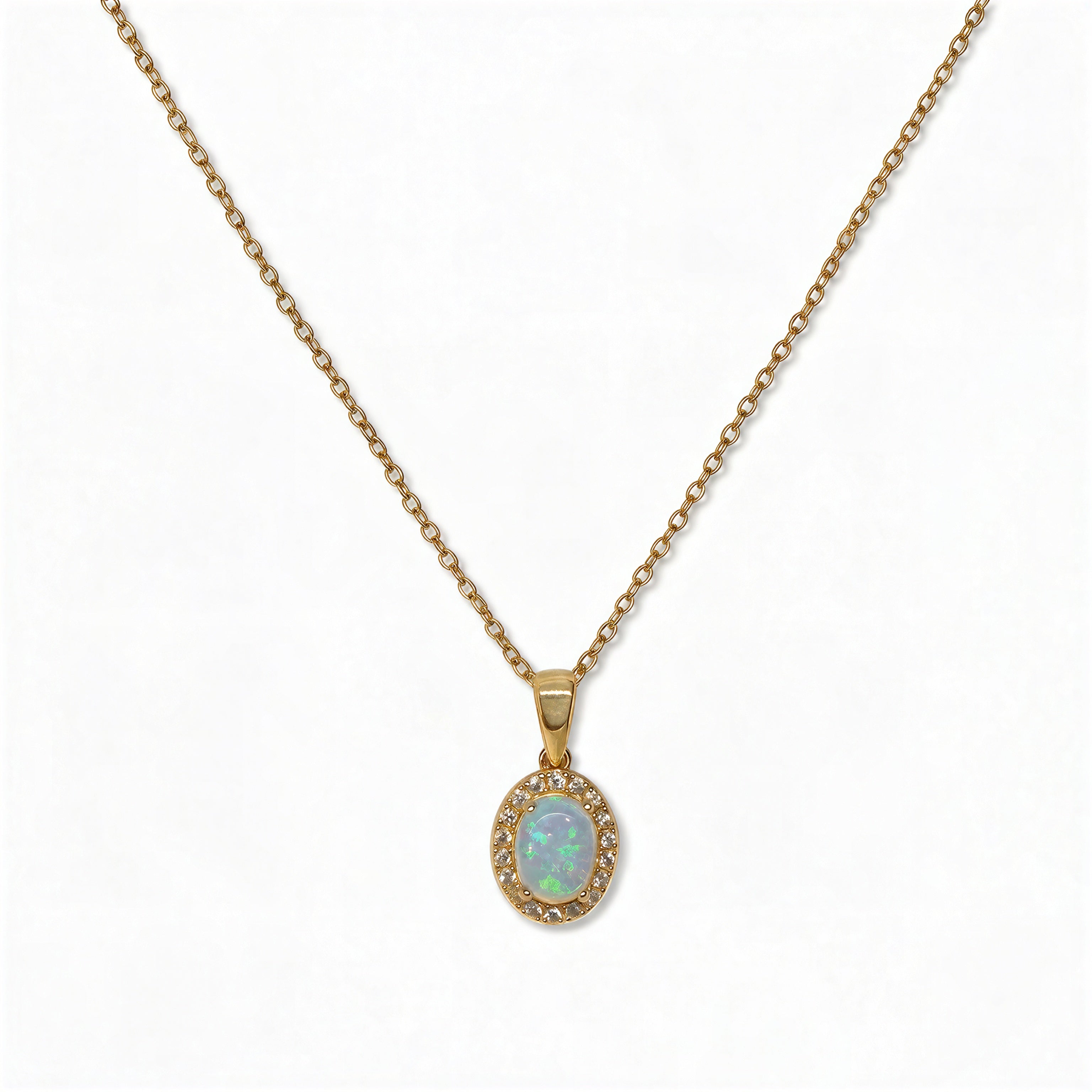 An Ethereal Opal with White Cubic Zirconia Halo Pendant Necklace by Skōsh Jewelry, featuring an oval iridescent opal framed by a halo of small clear stones on a fine gold chain, displayed against a white background.