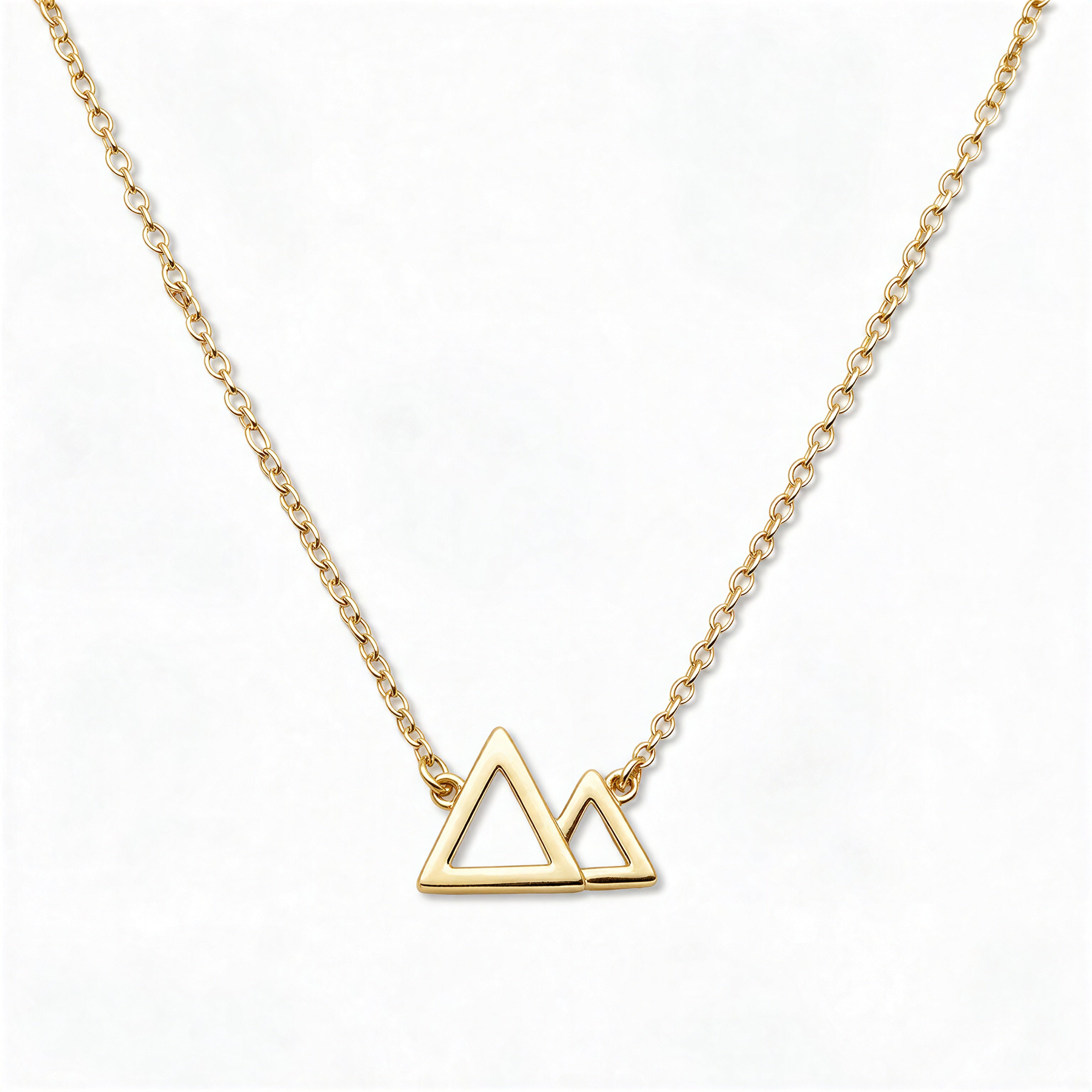 A Mountains and Valleys Necklace by Skōsh Jewelry, featuring an open outline of two mountain peaks set on a fine gold chain, displayed against a white background.