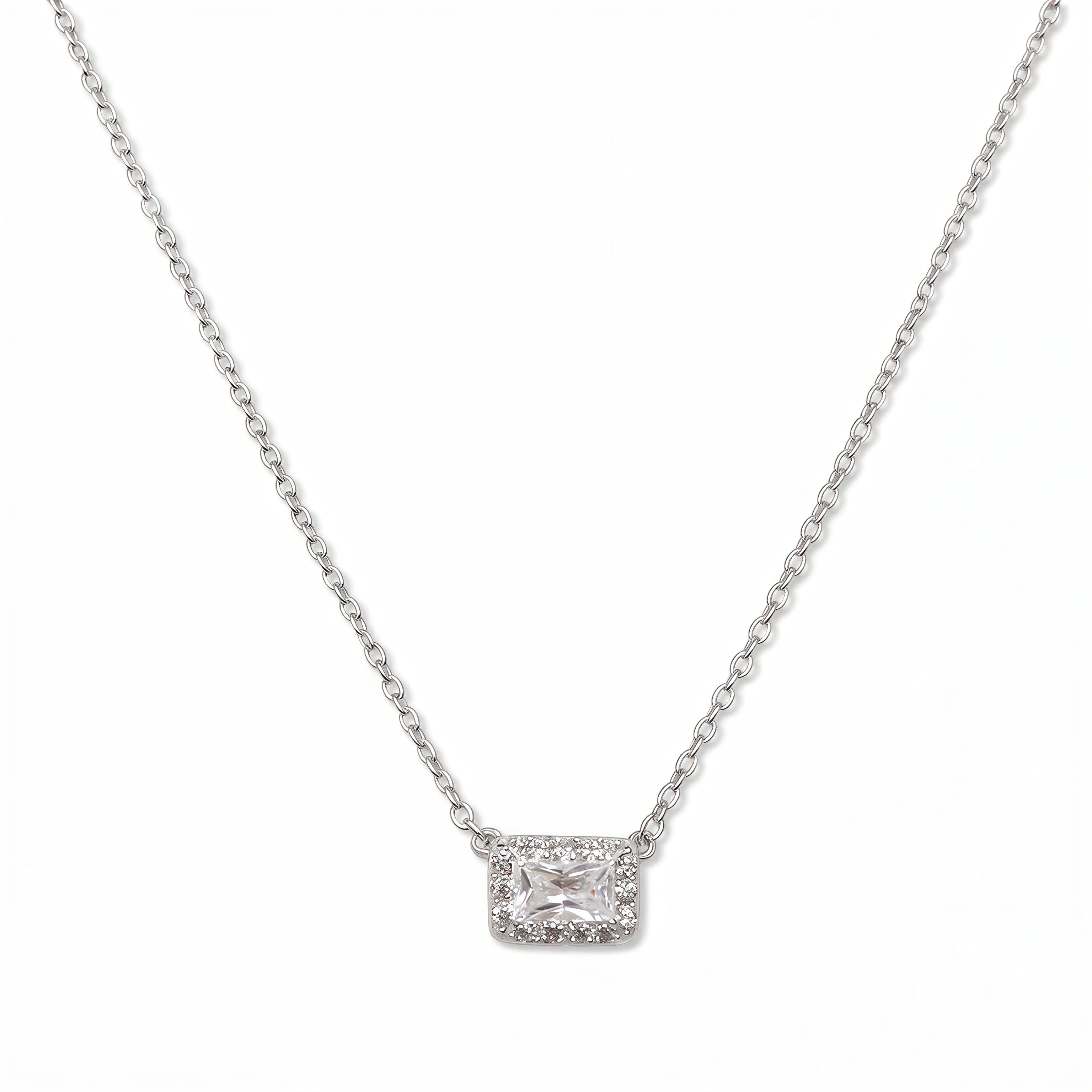A Radiant Grace Rectangle White Cubic Zirconia with Halo Necklace by Skōsh Jewelry, featuring a rectangular emerald-cut clear stone surrounded by a halo of smaller stones on a fine sterling silver chain, displayed against a white background.