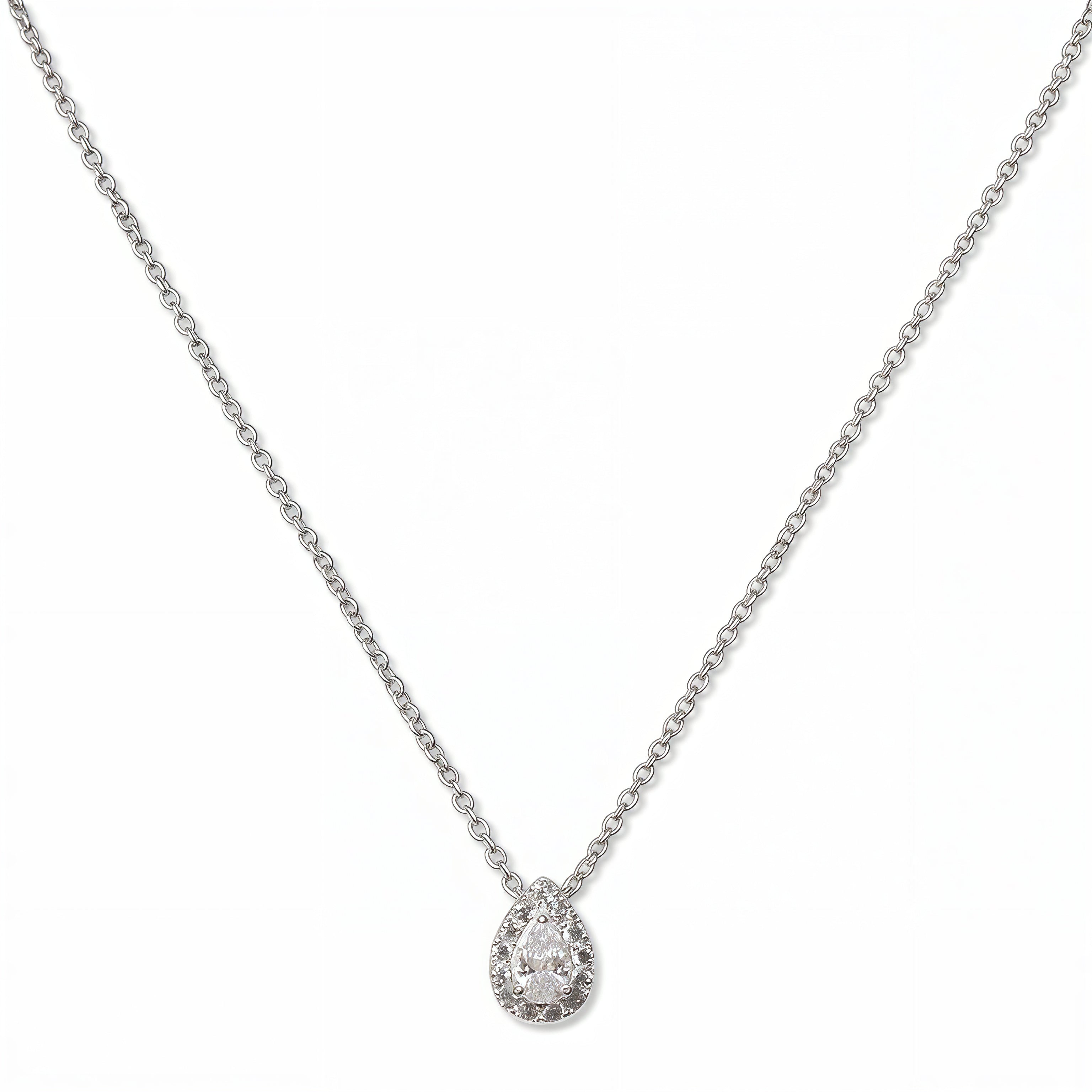 A Drop of Light Pear White Cubic Zirconia with Halo Necklace by Skōsh Jewelry, featuring a pear-shaped clear stone surrounded by a halo of smaller stones on a fine sterling silver chain, displayed against a white background.