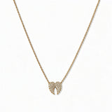 A Celestial Pavé White Cubic Zirconia Wings Necklace by Skōsh Jewelry, featuring a pair of angel wings covered in small clear pavé stones on a fine gold chain, displayed against a white background.