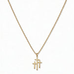 A Trinity Triple Cross Pendant Necklace by Skōsh Jewelry, featuring three slim crosses joined side by side, the center one tallest, on a fine gold chain, displayed against a white background.