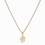 A Trinity Triple Cross Pendant Necklace by Skōsh Jewelry, featuring three slim crosses joined side by side, the center one tallest, on a fine gold chain, displayed against a white background.