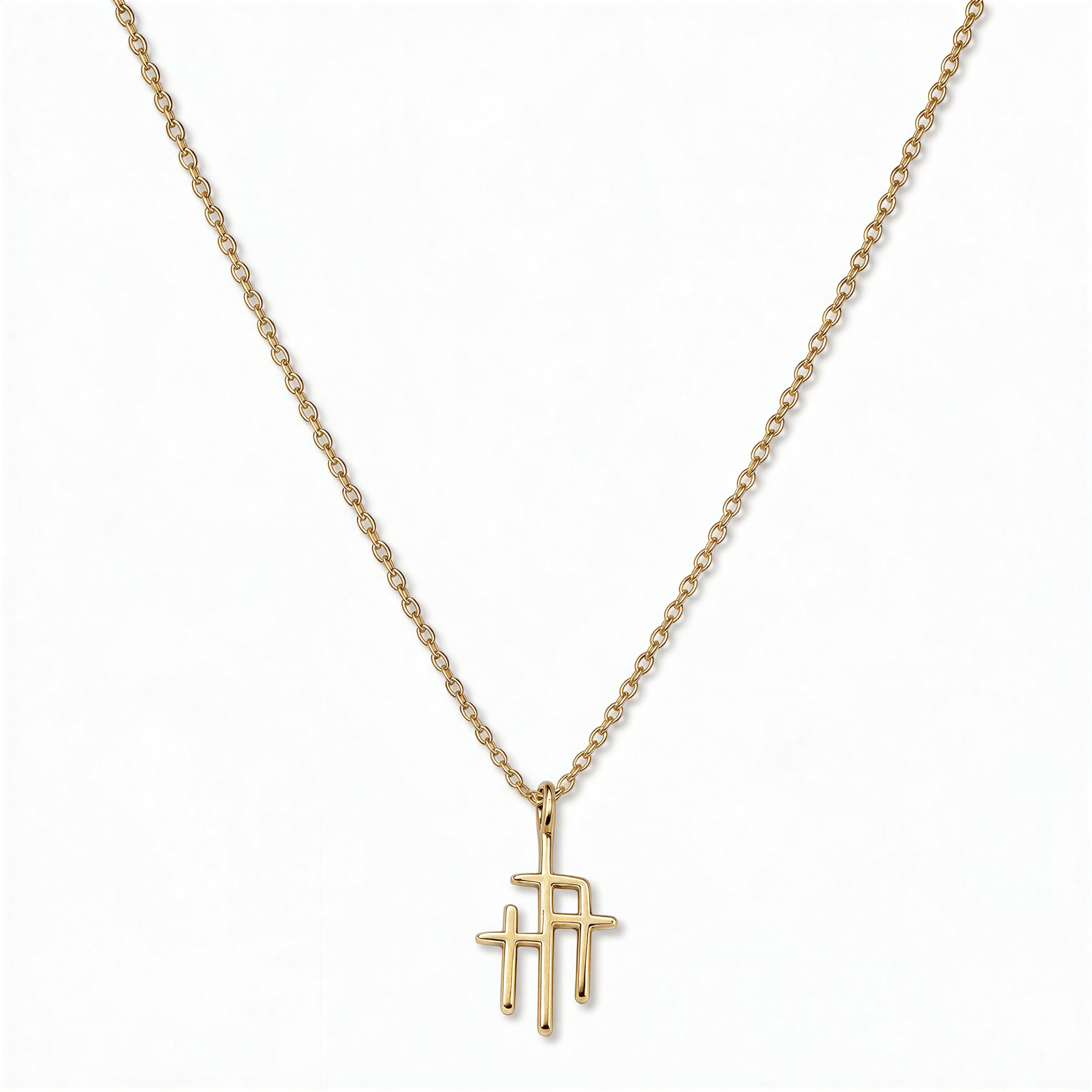 A Trinity Triple Cross Pendant Necklace by Skōsh Jewelry, featuring three slim crosses joined side by side, the center one tallest, on a fine gold chain, displayed against a white background.