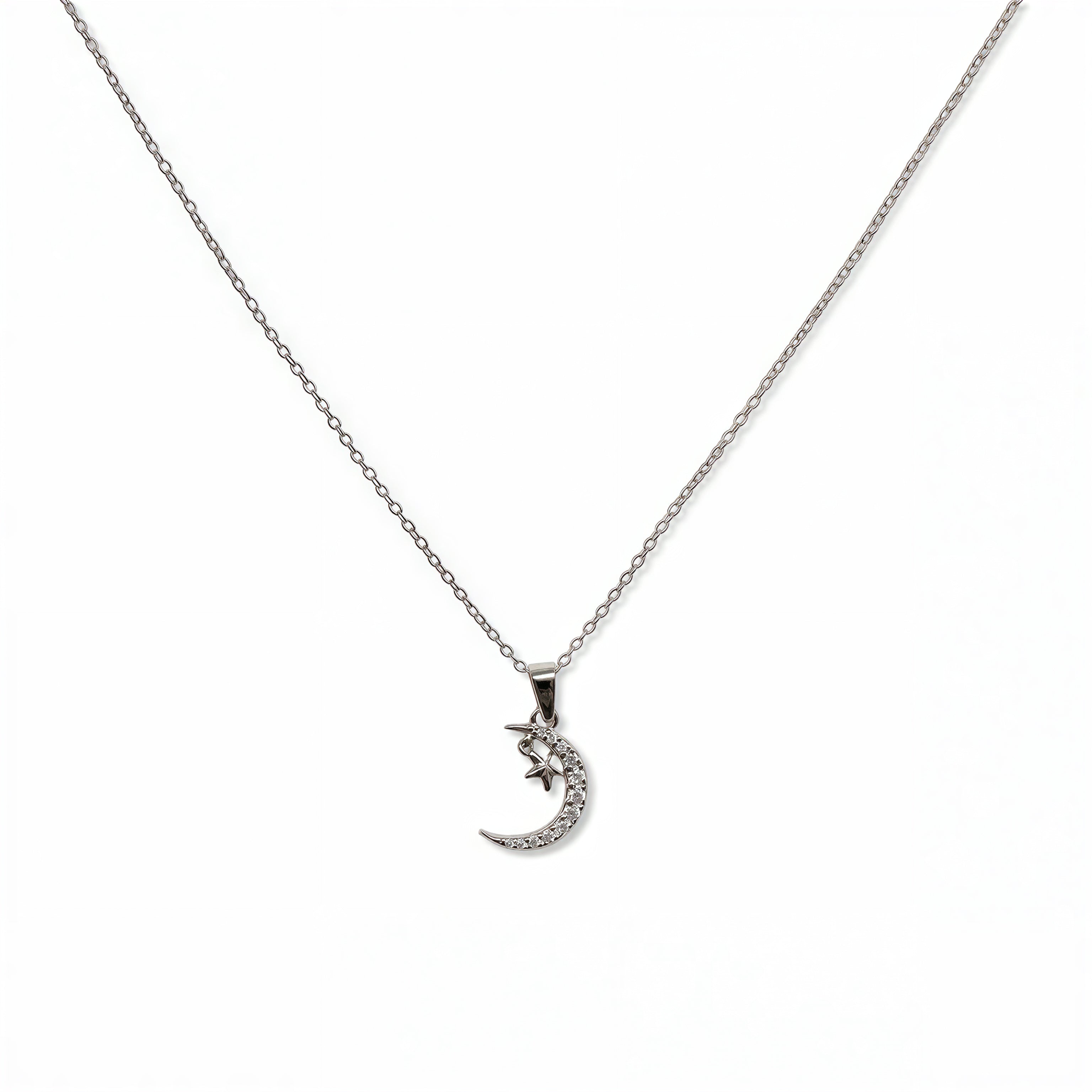 A Moon & Stars Pendant Necklace by Skōsh Jewelry, featuring a small crescent moon with a tiny star on a fine sterling silver chain, displayed against a white background.