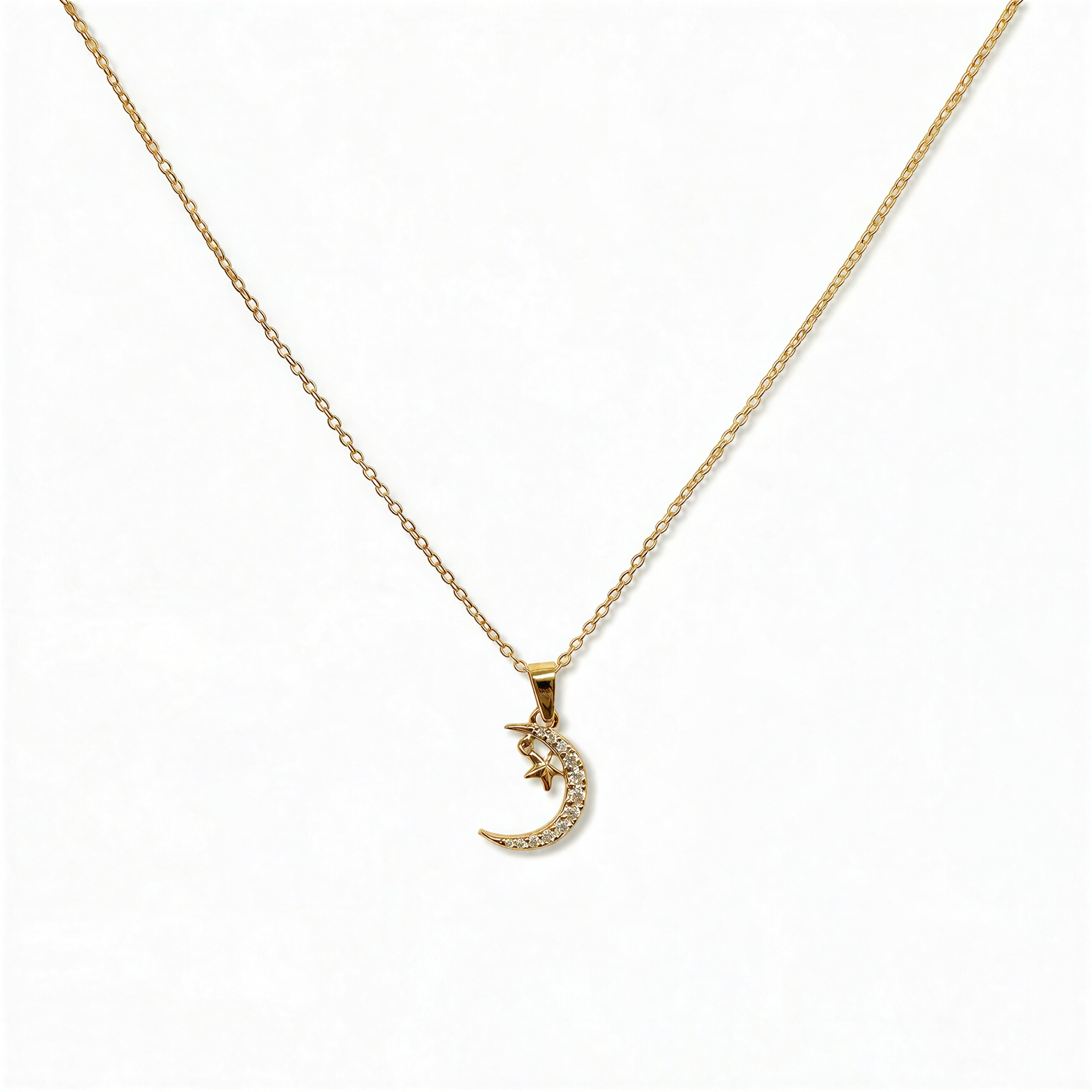 A Moon & Stars Pendant Necklace by Skōsh Jewelry, featuring a small crescent moon with a tiny star on a fine gold chain, displayed against a white background.