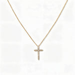 A Classic Light White Cubic Zirconia Cross Necklace by Skōsh Jewelry, featuring a classic cross lined with small clear stones on a fine gold chain, displayed against a white background.