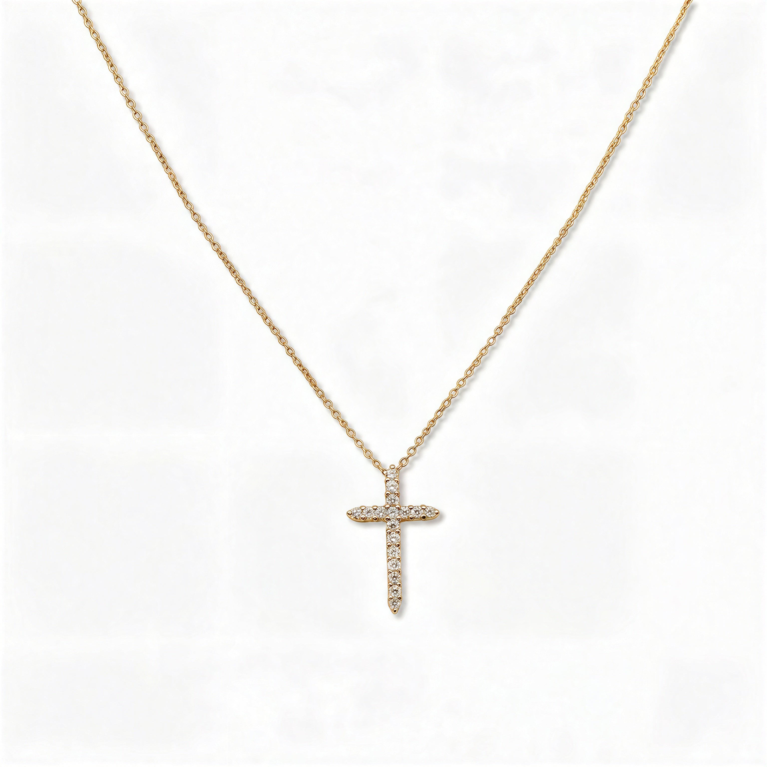 A Classic Light White Cubic Zirconia Cross Necklace by Skōsh Jewelry, featuring a classic cross lined with small clear stones on a fine gold chain, displayed against a white background.