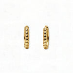 A pair of Beaded Huggie Hoop Earrings by Skōsh Jewelry, featuring small gold huggie hoops with a beaded texture, displayed against a white background.
