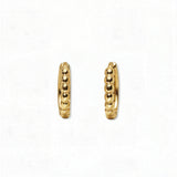 A pair of Beaded Huggie Hoop Earrings by Skōsh Jewelry, featuring small gold huggie hoops with a beaded texture, displayed against a white background.