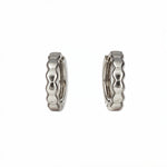 A pair of Hexagon Huggie Hoop Earrings by Skōsh Jewelry, featuring small sterling silver huggie hoops with a faceted hexagon texture, displayed against a white background.