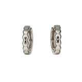 A pair of Hexagon Huggie Hoop Earrings by Skōsh Jewelry, featuring small sterling silver huggie hoops with a faceted hexagon texture, displayed against a white background.
