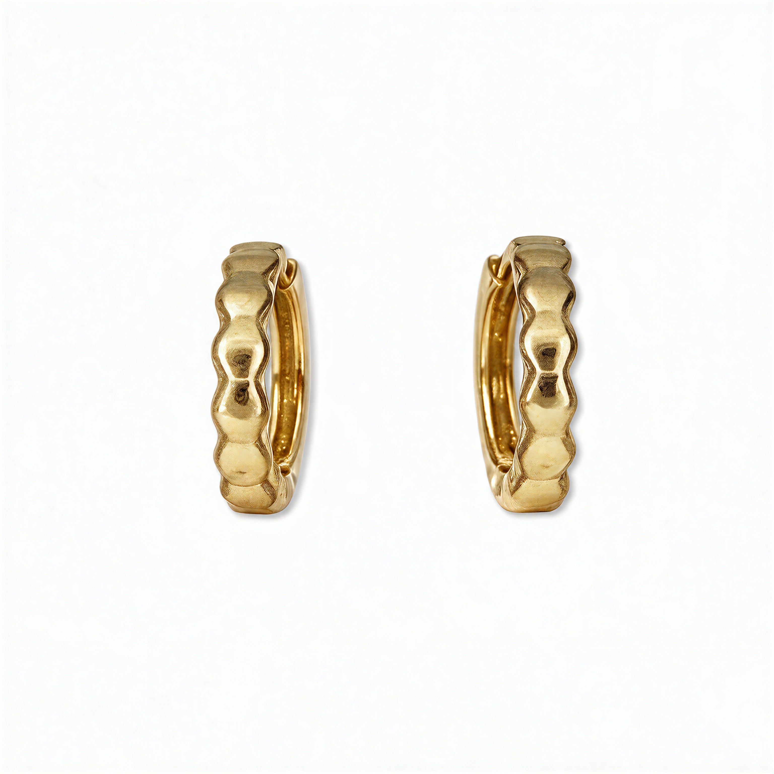 A pair of Hexagon Huggie Hoop Earrings by Skōsh Jewelry, featuring small gold huggie hoops with a faceted hexagon texture, displayed against a white background.