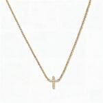 An Endless Faith Mini Cross with White Cubic Zirconia Necklace by Skōsh Jewelry, featuring a petite cross lined with small clear stones set on a fine gold chain, displayed against a white background.