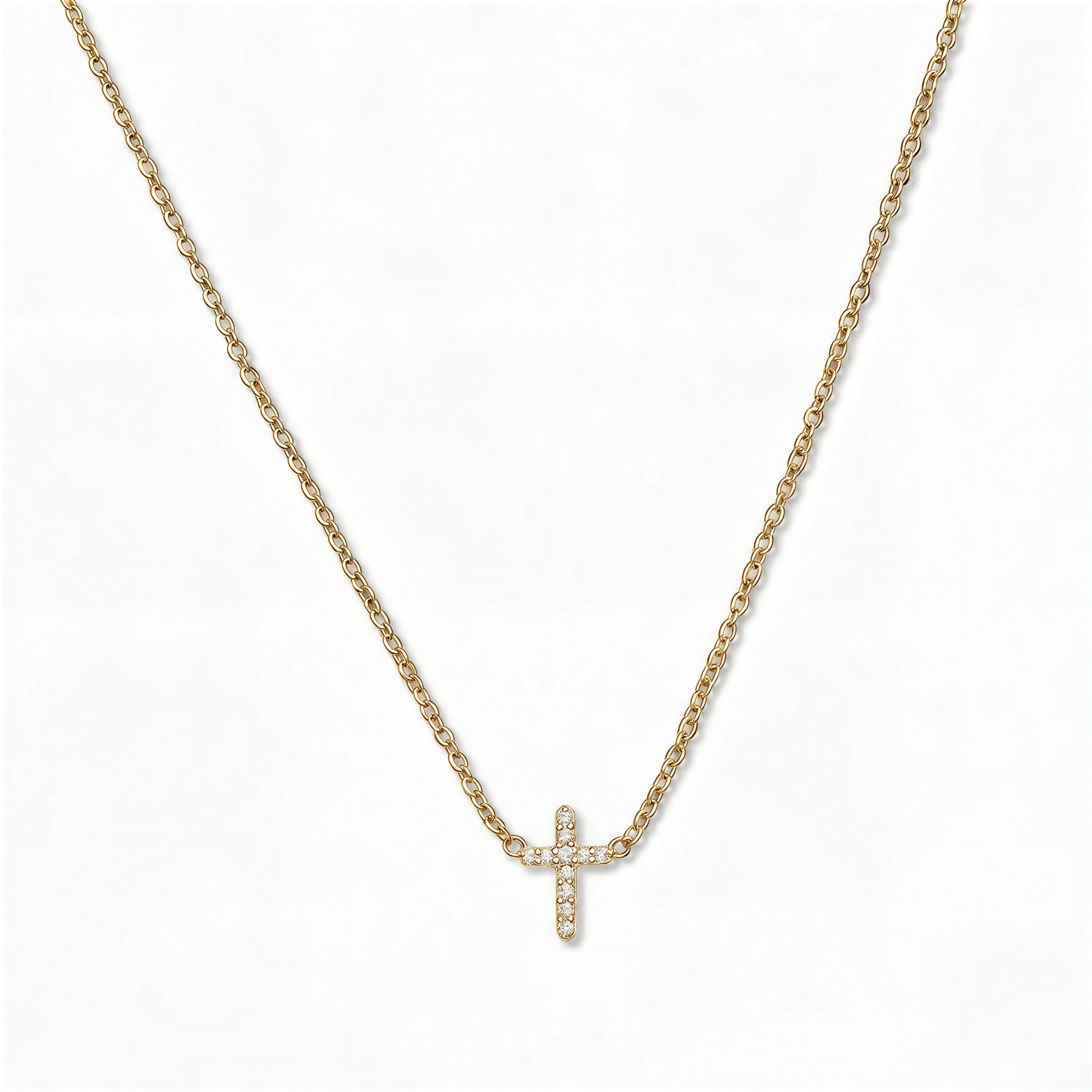 An Endless Faith Mini Cross with White Cubic Zirconia Necklace by Skōsh Jewelry, featuring a petite cross lined with small clear stones set on a fine gold chain, displayed against a white background.