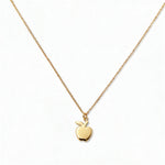 An Apple Pendant Necklace by Skōsh Jewelry, featuring a small polished apple pendant with a leaf on a fine gold chain, displayed against a white background.