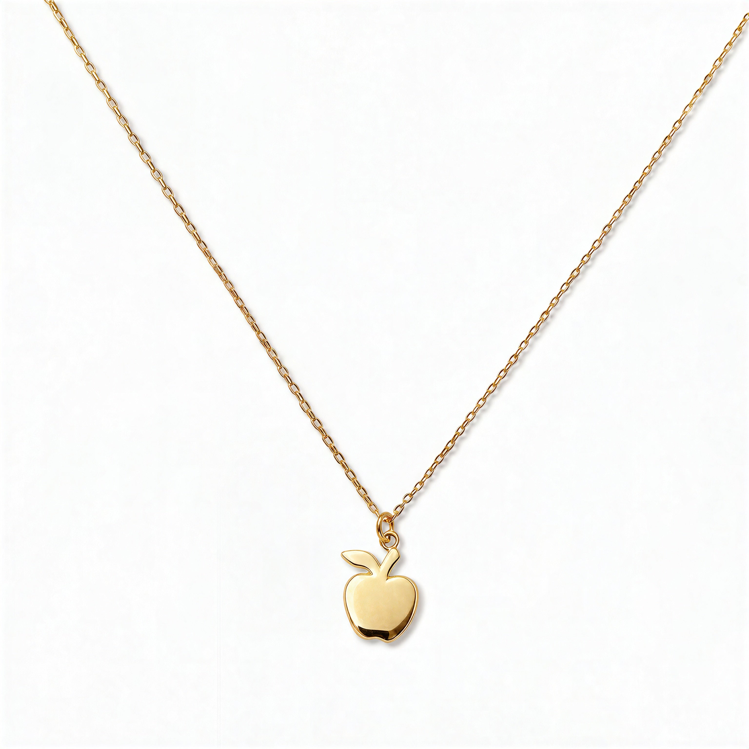 An Apple Pendant Necklace by Skōsh Jewelry, featuring a small polished apple pendant with a leaf on a fine gold chain, displayed against a white background.