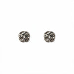 A pair of Knotted Stud Earrings by Skōsh Jewelry, featuring polished sterling silver studs shaped like twisted love knots, displayed against a white background.