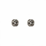 A pair of Knotted Stud Earrings by Skōsh Jewelry, featuring polished sterling silver studs shaped like twisted love knots, displayed against a white background.