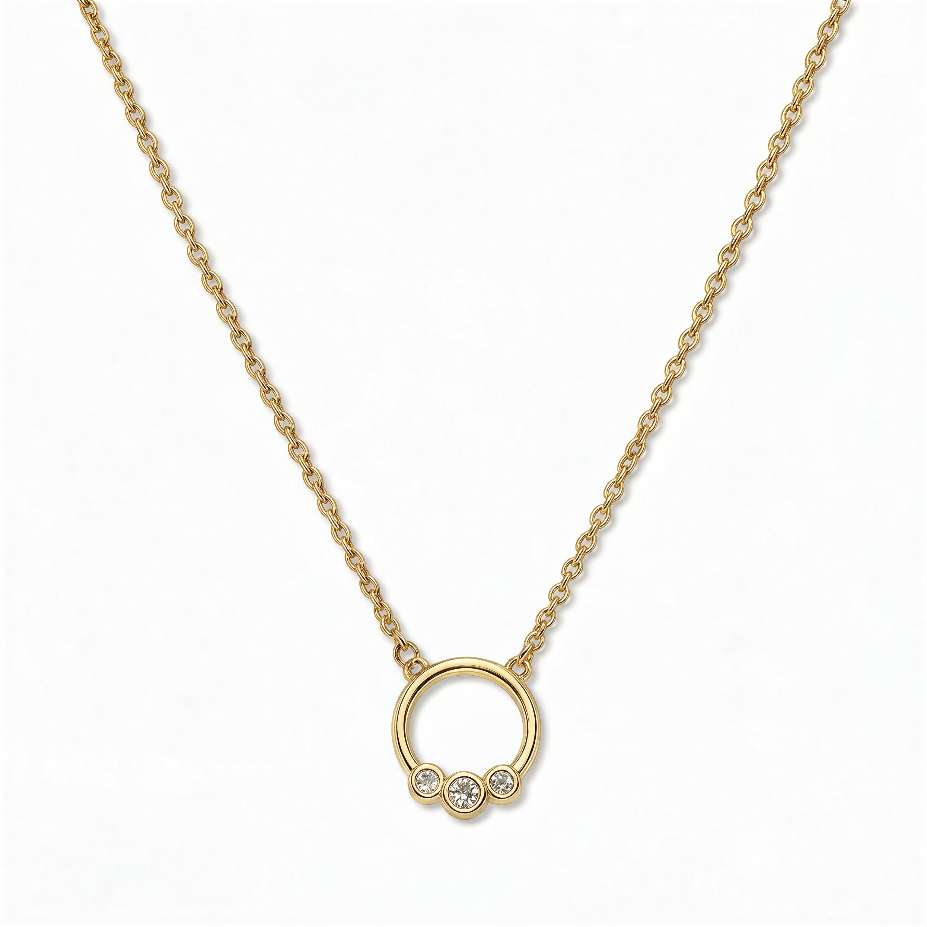 A Trio White Cubic Zirconia Accent Circle Necklace by Skōsh Jewelry, featuring a small open circle accented with three clear stones on a fine gold chain, displayed against a white background.