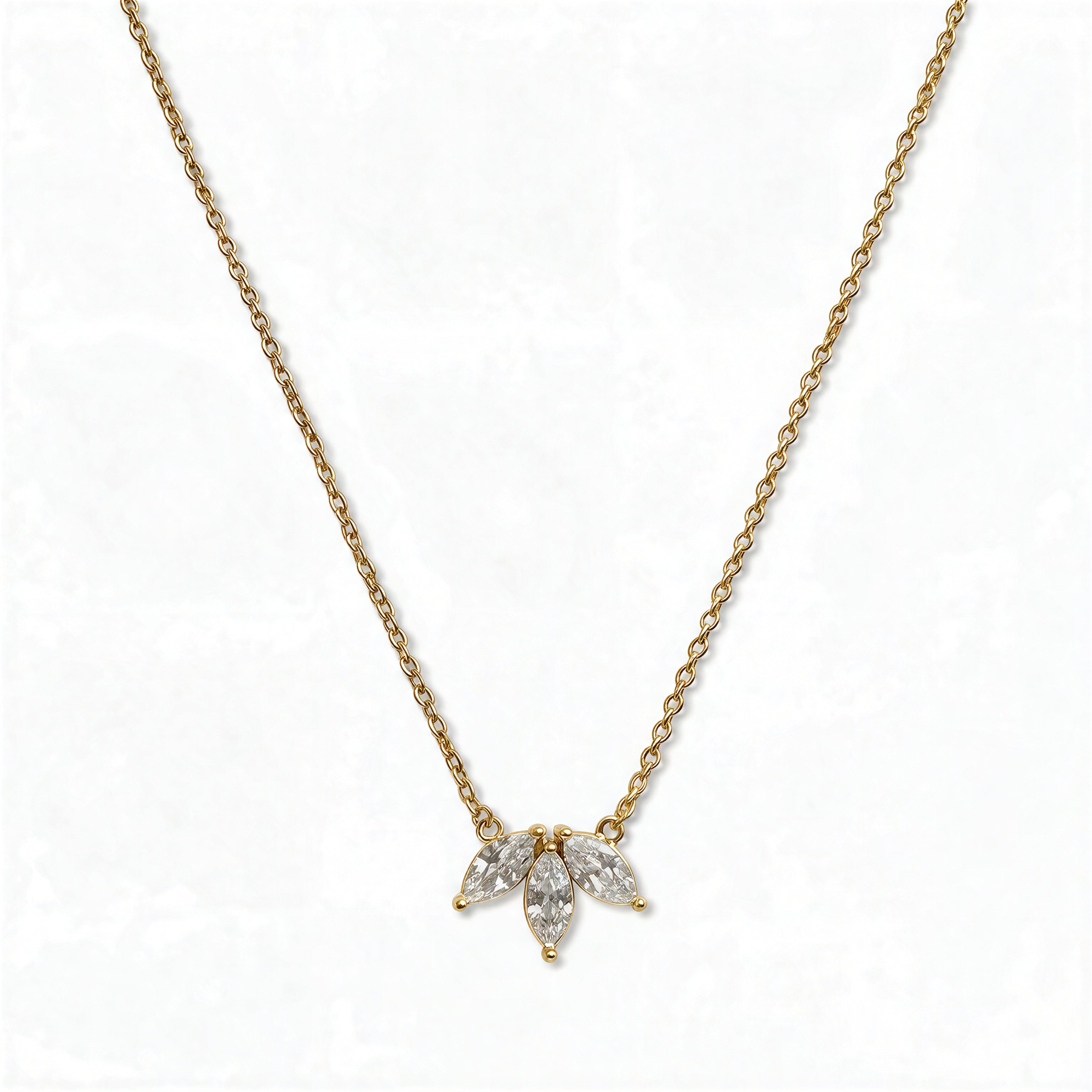 A Triple Marquise Cut White Cubic Zirconia Necklace by Skōsh Jewelry, featuring three marquise-cut clear stones fanned in a row on a fine gold chain, displayed against a white background.