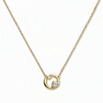 A Karma Double White Cubic Zirconia Accent Circle Necklace by Skōsh Jewelry, featuring an open circle with two clear stone accents on a fine gold chain, displayed against a white background.
