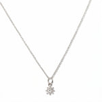 A Sunburst White Cubic Zirconia Pendant Necklace by Skōsh Jewelry, featuring a small sunburst pendant with a clear stone at its center on a fine sterling silver chain, displayed against a white background.