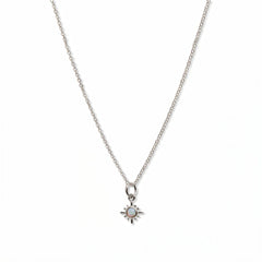 A Sunburst Opal Pendant Necklace by Skōsh Jewelry, featuring a tiny sunburst pendant with an opal center on a fine sterling silver chain, displayed against a white background.