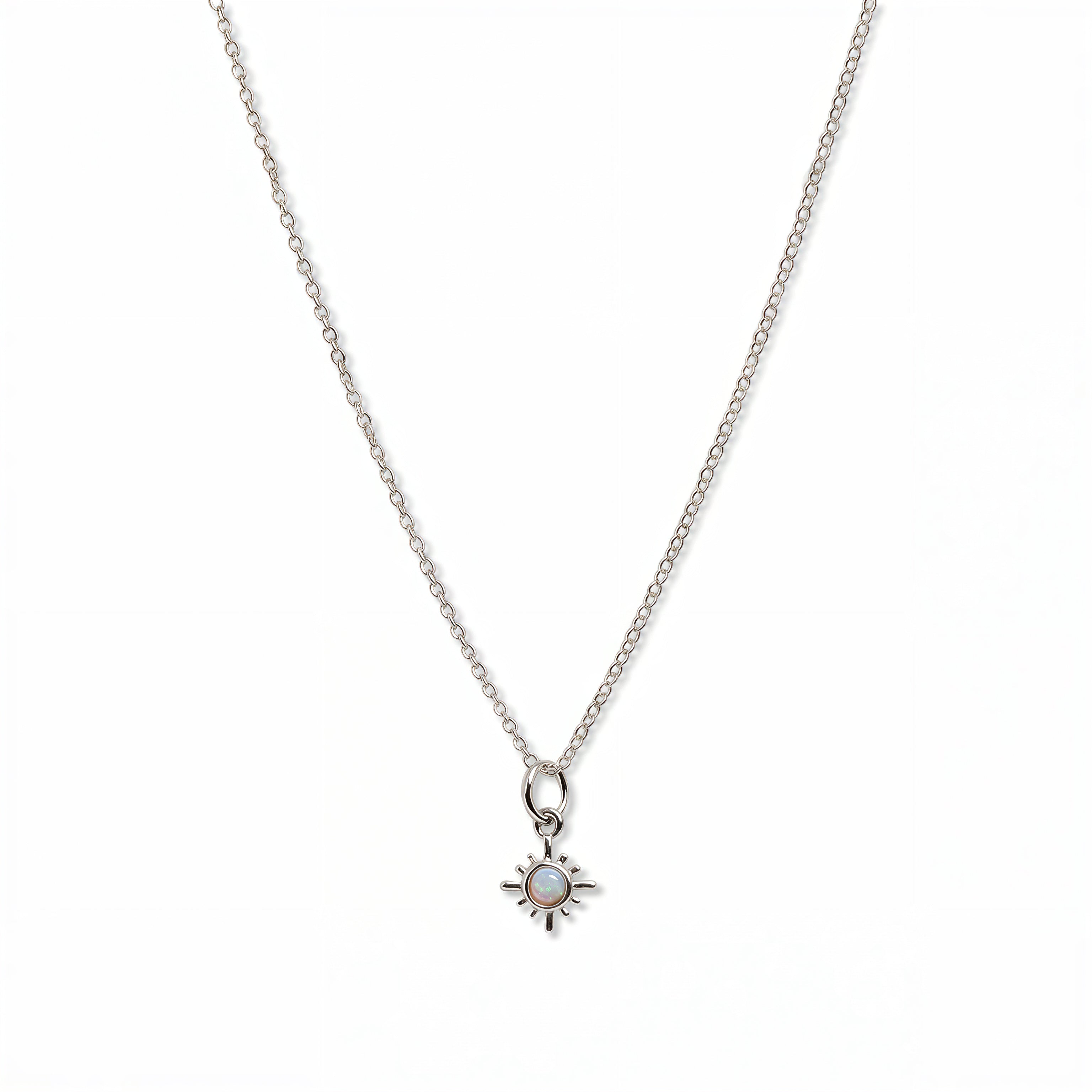 A Sunburst Opal Pendant Necklace by Skōsh Jewelry, featuring a tiny sunburst pendant with an opal center on a fine sterling silver chain, displayed against a white background.