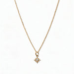 A Sunburst Opal Pendant Necklace by Skōsh Jewelry, featuring a tiny sunburst pendant with an opal center on a fine gold chain, displayed against a white background.