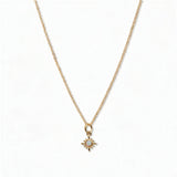 A Sunburst Opal Pendant Necklace by Skōsh Jewelry, featuring a tiny sunburst pendant with an opal center on a fine gold chain, displayed against a white background.