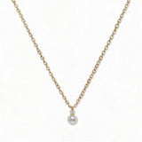 A Classic Drop Pearl with White Cubic Zirconia Accent Necklace by Skōsh Jewelry, featuring a round white freshwater pearl drop topped with a small clear stone on a fine gold chain, displayed against a white background.