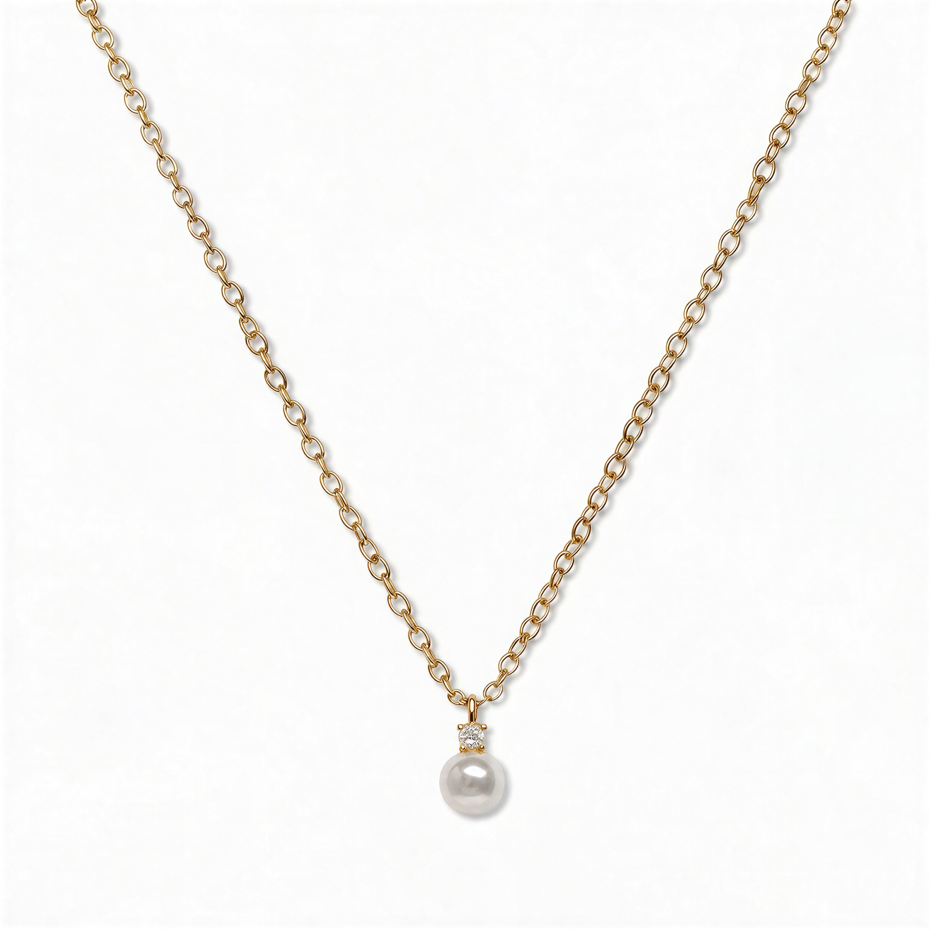 A Classic Drop Pearl with White Cubic Zirconia Accent Necklace by Skōsh Jewelry, featuring a round white freshwater pearl drop topped with a small clear stone on a fine gold chain, displayed against a white background.