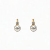 A pair of Classic Pearl with White Cubic Zirconia Accent Earrings by Skōsh Jewelry, featuring round white freshwater pearl drops topped with small clear stones in gold, displayed against a white background.