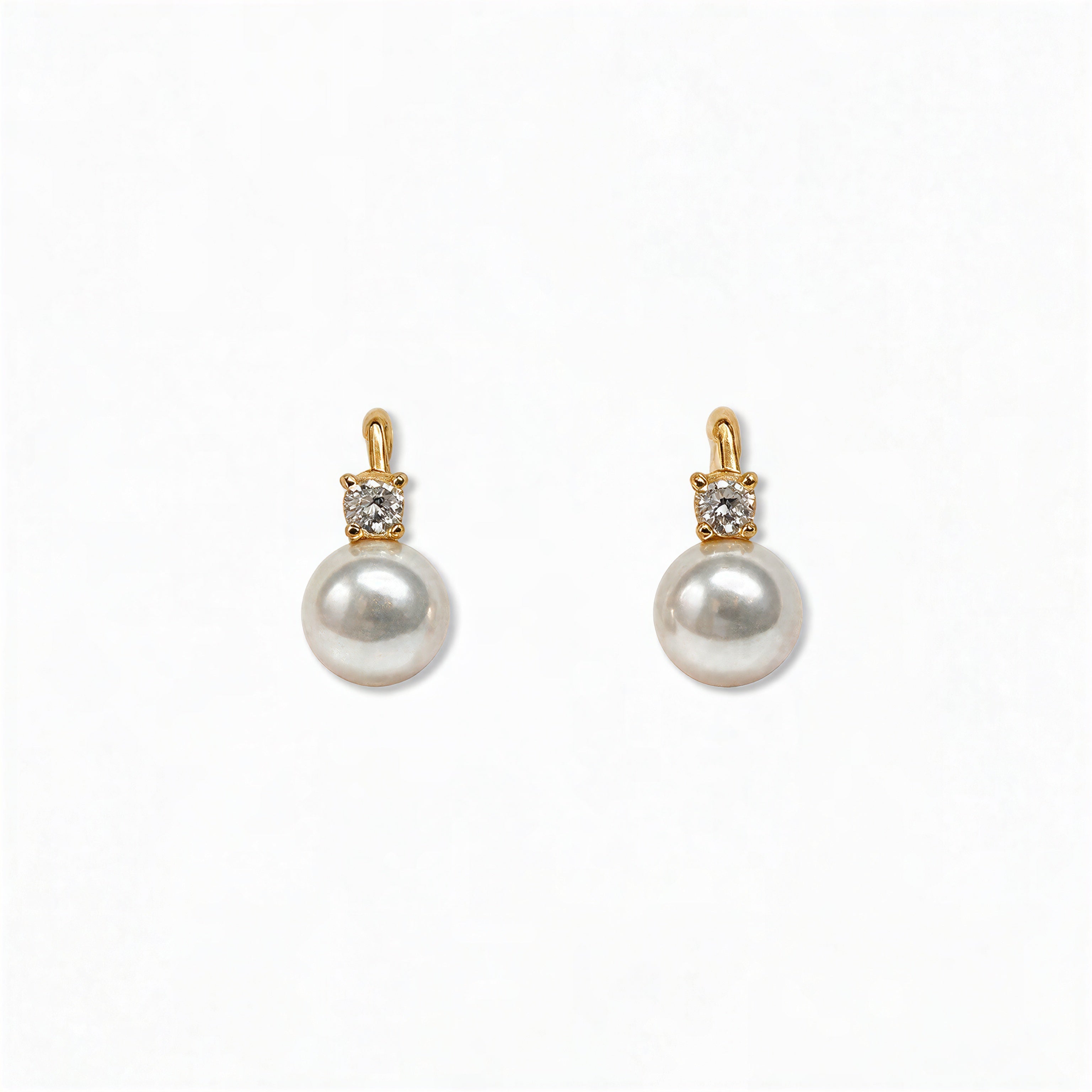 A pair of Classic Pearl with White Cubic Zirconia Accent Earrings by Skōsh Jewelry, featuring round white freshwater pearl drops topped with small clear stones in gold, displayed against a white background.
