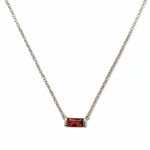 A January Birthstone Garnet Cubic Zirconia Baguette Necklace by Skōsh Jewelry, featuring a slim rectangular deep red baguette stone set horizontally on a fine sterling silver chain, displayed against a white background.