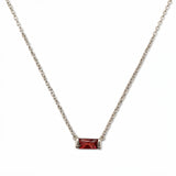 A January Birthstone Garnet Cubic Zirconia Baguette Necklace by Skōsh Jewelry, featuring a slim rectangular deep red baguette stone set horizontally on a fine sterling silver chain, displayed against a white background.