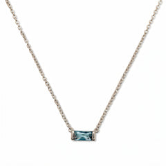 A March Birthstone Light Sapphire Cubic Zirconia Baguette Necklace by Skōsh Jewelry, featuring a slim rectangular light blue baguette stone set horizontally on a fine sterling silver chain, displayed against a white background.