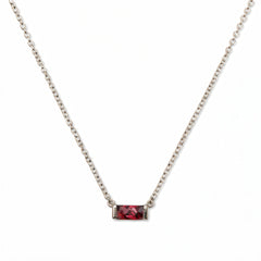 A July Birthstone Ruby Cubic Zirconia Baguette Necklace by Skōsh Jewelry, featuring a slim rectangular red baguette stone set horizontally on a fine sterling silver chain, displayed against a white background.