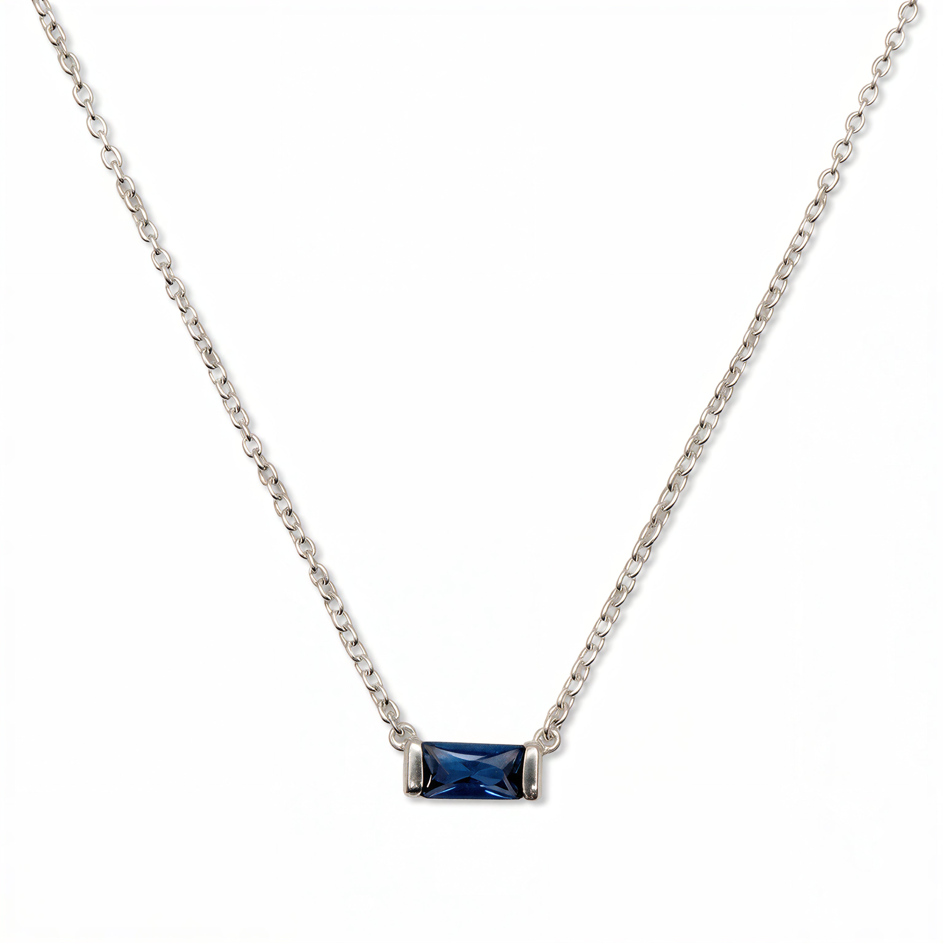 A September Birthstone Sapphire Cubic Zirconia Baguette Necklace by Skōsh Jewelry, featuring a slim rectangular deep blue baguette stone set horizontally on a fine sterling silver chain, displayed against a white background.
