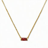A January Birthstone Garnet Cubic Zirconia Baguette Necklace by Skōsh Jewelry, featuring a slim rectangular deep red baguette stone set horizontally on a fine gold chain, displayed against a white background.